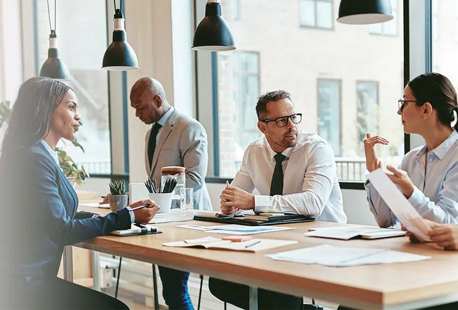 four people at a desk while at work discussing leadership