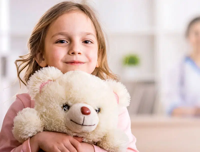 child hugging a stuffed bear